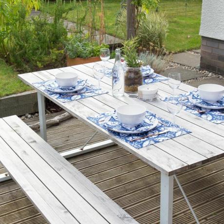 白いピクニック テーブルとベンチ、青い模様の場所設定