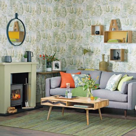 Útulný obývací pokoj s celoplošnými stromovými zelenými tapetami a šedou pohovkou
