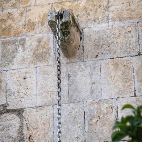 Отблизо метална дъждовна верига върху каменна стена