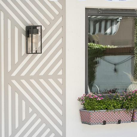 färgglad trädgård med spaljéskärm på vägg och fönsterlåda