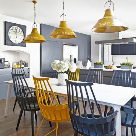 køkken og spiseplads med træstole i marineblå og gul