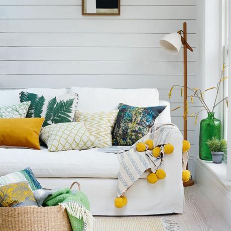 白いパネルの壁、白いソファ、木製のフロアランプを備えたリビング ルーム