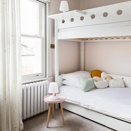 חדר שינה לבנות עם מיטת קומותיים לבנה, גוף תאורה לבן ועיצוב וילון לבן עם מוטיב כוכבים מודפס זהב