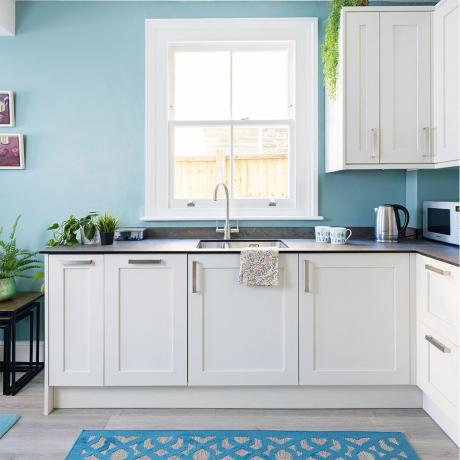 vitt kök med blå väggar och svarta bänkskivor