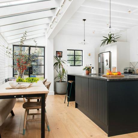 ห้องครัวพร้อมไอส์แลนด์สีดำ โต๊ะทานอาหาร และเพดานสูง