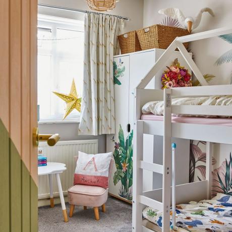 Kinderzimmer mit weißen Etagenbetten und weißem Kleiderschrank mit tropischem Druckmuster