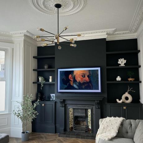 stue med sorte vægge og tidstypiske detaljer som loftrose og udsmykket pejs