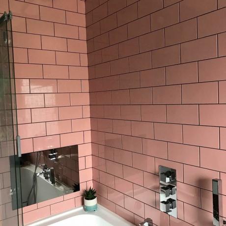 Relooking de salle de bain avec carrelage rose, lambris gris et papier peint à imprimé tropical
