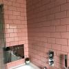 Przeróbka łazienki z różowymi płytkami, szarą boazerią i tapetą z tropikalnym nadrukiem