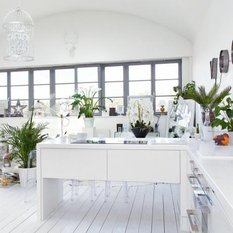 Λευκό ενιαίο σαλόνι κουζίνας με βαμμένες σανίδες δαπέδου και κρεμαστό φωτιστικό