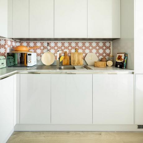 Balta virtuvė su raštuotomis plytelėmis išklotomis backsplash