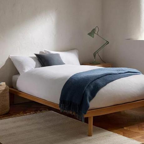 إطار سرير خشبي مع فراش أبيض في الأعلى
