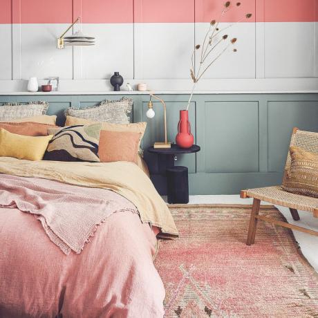 golvidéer för sovrum, rosa och gula sängkläder, grå paneler med rosa rand, rosa vintage matta, trästol