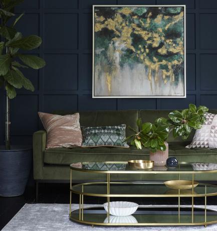 Mėlyna svetainė su žalia sofa ir sienų menais