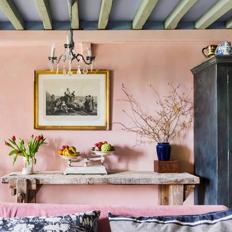 天井に灰色の塗装された梁のあるピンクのリビングルーム