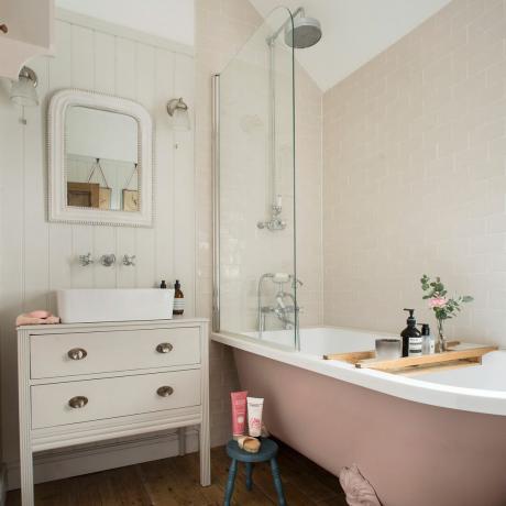 Neutraali kylpyhuone, jossa paneloidut seinät ja vaaleanpunainen kylpyamme