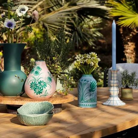 Vaisselle keramikinės vazos ant medinio lauko stalo šalia žvakidžių.