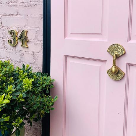 Números de puerta de latón de Gipsy Hill Hardware y aldaba en una puerta delantera rosa chicle