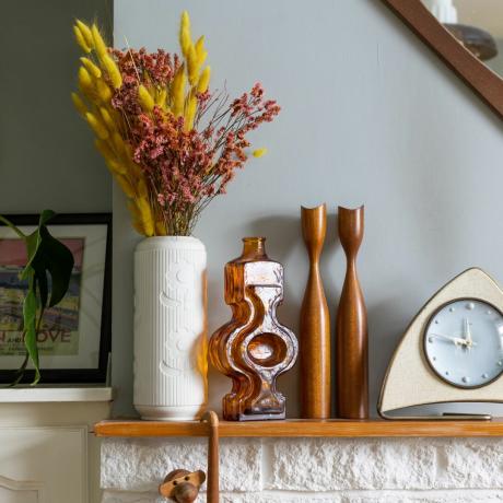 Дървена камина с оранжево, дървени декоративни елементи и бяла ваза с оранжеви цветя