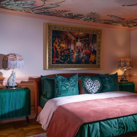 sovrum med tapetserat tak och gröna och rosa sängkläder