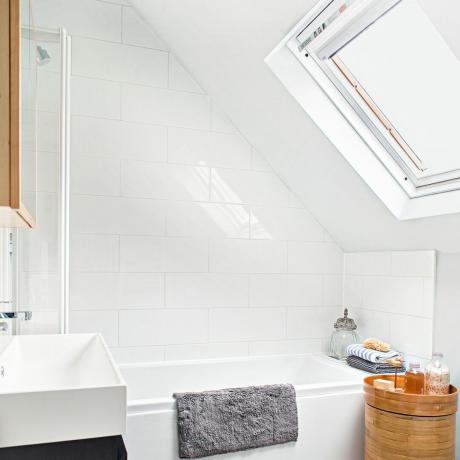 Balta bēniņu vannas istaba ar jumta logu un vannu