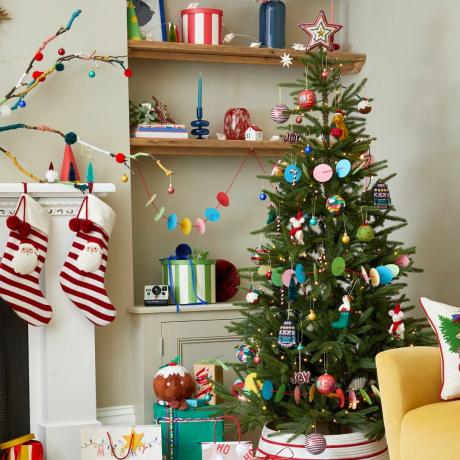 Een vrolijk versierde kerstboom in een versierde woonkamer
