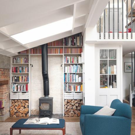 Woonkamer met witte muren, houtkachel en ingebouwde boekenkasten.