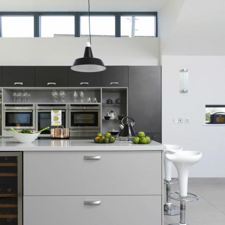minimalistisk monokromt kjøkken med øy, barkrakker og belysning