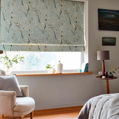 Persiana de color huevo de pato pálido con un diseño de flor de cerezo en la ventana de una sala de estar