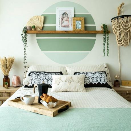 Dormitorio con bandeja de desayuno sobre la cama y decoración de pared en macramé.