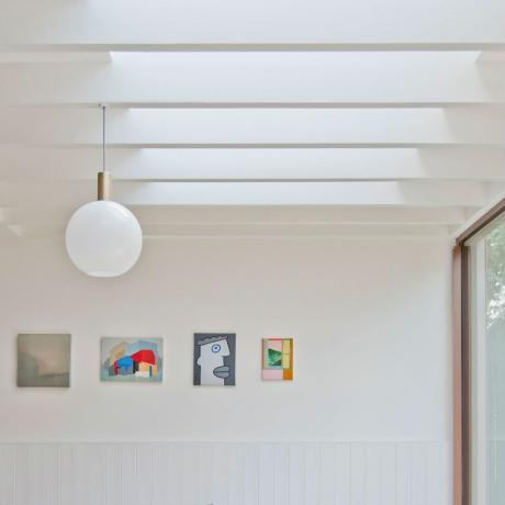 lamelová střecha se světlíky, terasové dveře, závěsné světlo a umělecká díla na stěně