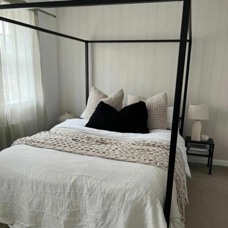 dormitorio con cama con dosel negro y cojines
