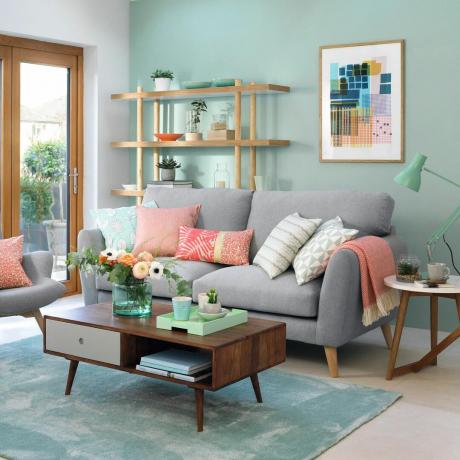 غرفة معيشة مع أبواب فناء خارجية للحديقة ، وجدران مطلية باللون الأخضر النعناعي وأريكة رمادية ناعمة