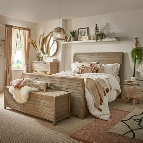 ห้องนอนที่เป็นกลางพร้อมเตียงไม้และชั้นวางของที่มีต้นไม้เขียวขจี