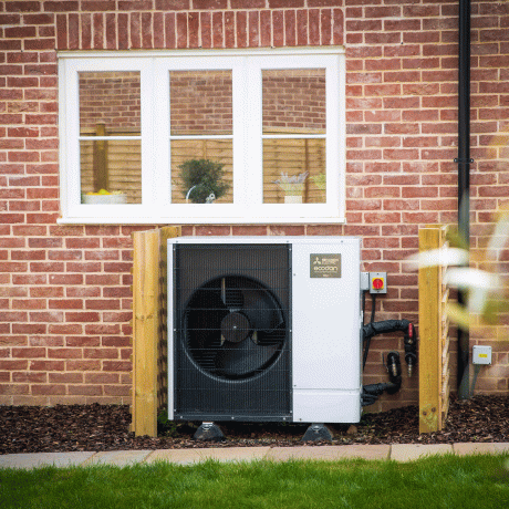 Bijela toplinska pumpa izvan kuće od cigle