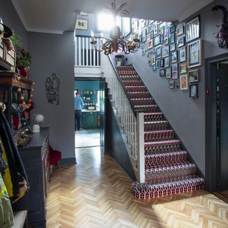 Pasillo gris oscuro con alfombra de escalera estampada y pared de galería de imágenes