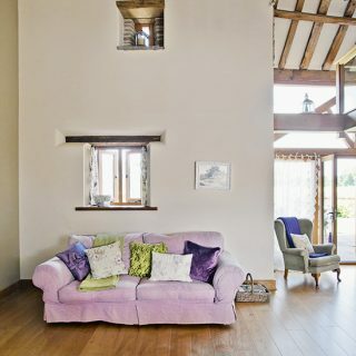 Lantligt vardagsrum i dubbelhöjd med rosa soffa