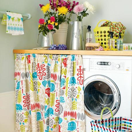 Iš arti skalbimo mašinos su gėlių užuolaida