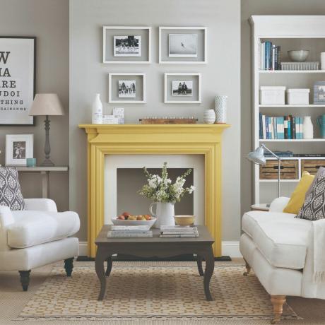 Šedý obývací pokoj se žlutými akcenty, centrální krb se žlutým pláštěm