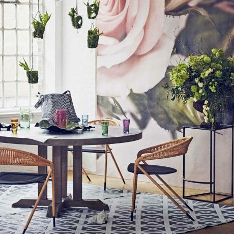 Sala de jantar botânica com mesa de concreto e mural de rosas