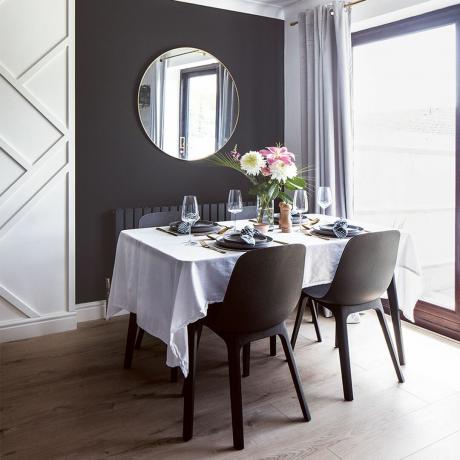غرفة طعام بجدران مغطاة بألواح سوداء وبيضاء وطاولة طعام وكراسي