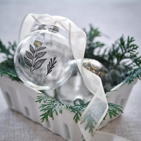 Julekule i glass med blomstermotiv og bånd i boks med bladverk