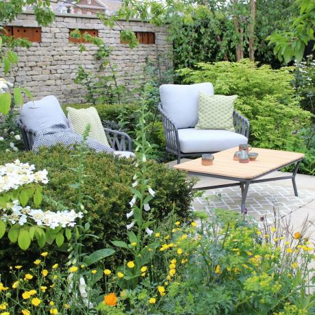 Une paire de fauteuils de jardin nichés parmi les bordures vertes d'un jardin
