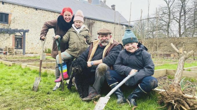 Dick și Angel Strawbridge și copiii lor în grădina lor cu unelte de grădinărit