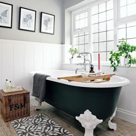 Σκούρα μπανιέρα σε λευκό μπάνιο με καλάθι αποθήκευσης και χαλάκι μπάνιου