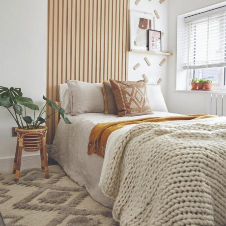 Dormitorio con paneles de madera y una manta tejida sobre la cama