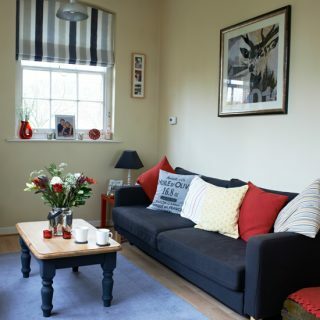 Klassiskt neutralt vardagsrum med röda och blå detaljer