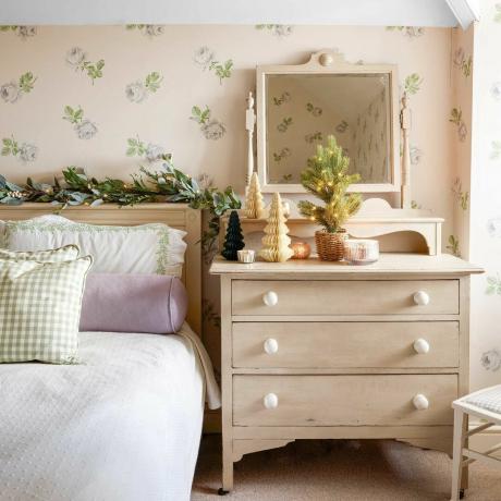 dormitorio de estilo rústico con papel tapiz floral y tocador reciclado