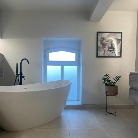 badrum med fristående badkar och svart golvkran