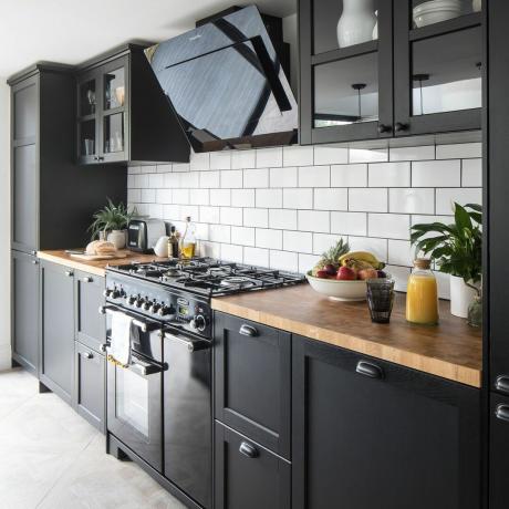 Cocina con gabinetes negros y salpicadero de azulejos color blanco